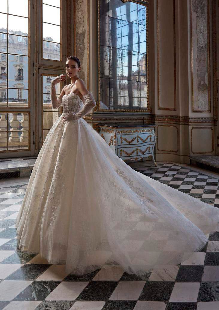 Woman wearing a voluminous tulle princess-cut wedding gown, posing elegantly in a ballroom