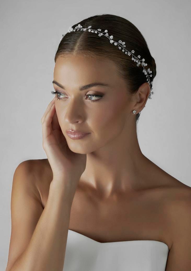 Brunette wearing a strapless wedding dress and a delicate bridal headpiece, gazing to the side