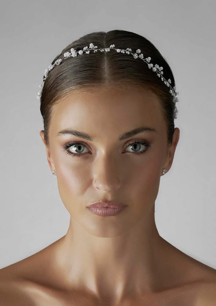 Face of a woman adorned with a pearl wedding headpiece, wearing stylish makeup