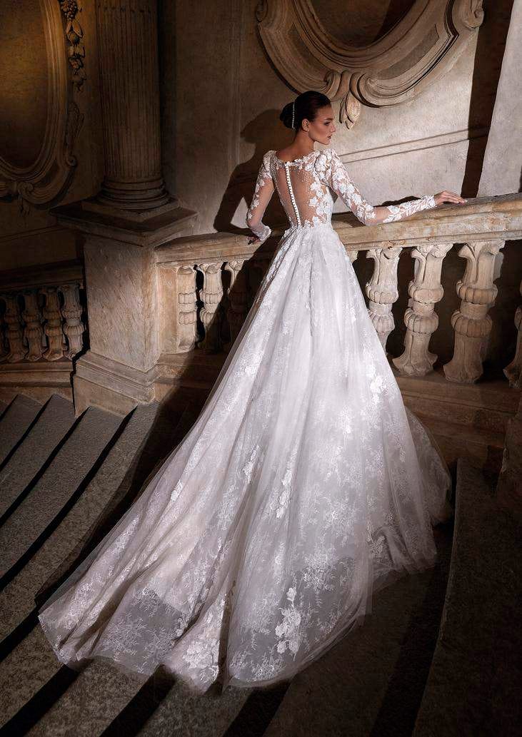 Woman in an A-line princess wedding dress with a flowing lace tulle skirt, standing on a staircase