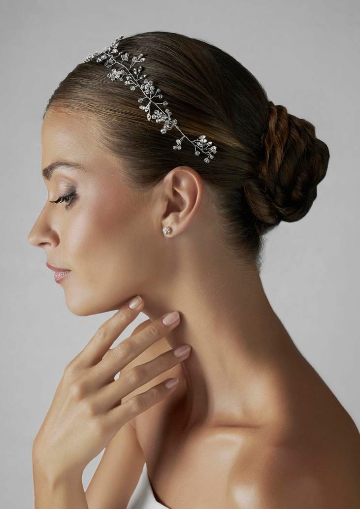 Brunette in a strapless wedding dress with a stylish hairstyle and makeup, wearing a floral bridal headpiece